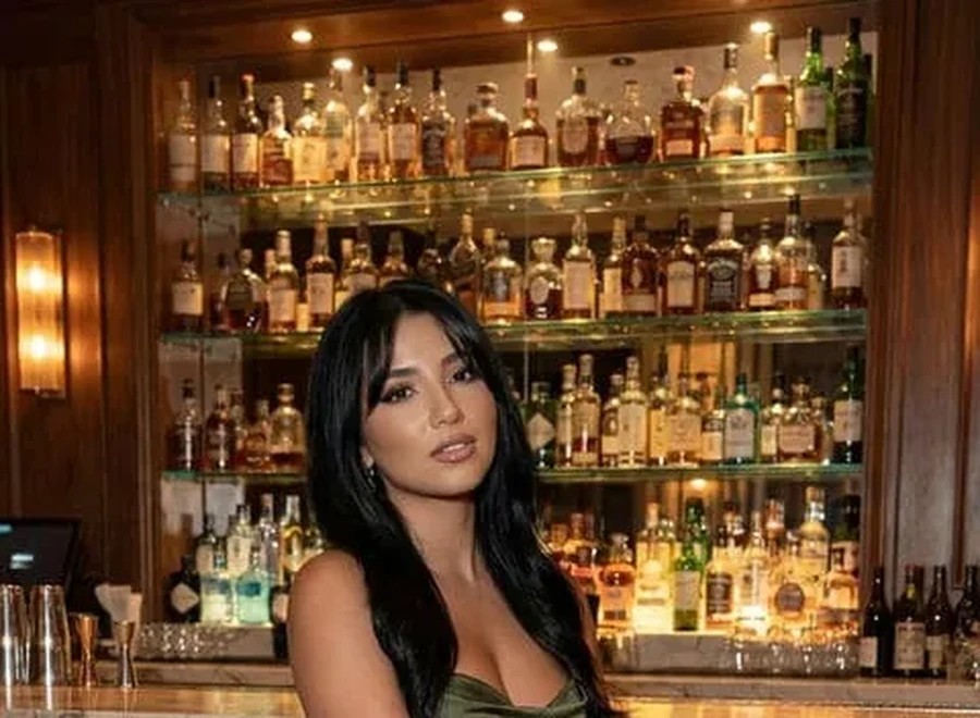 Female findom in an elegant green dress at a cocktail bar